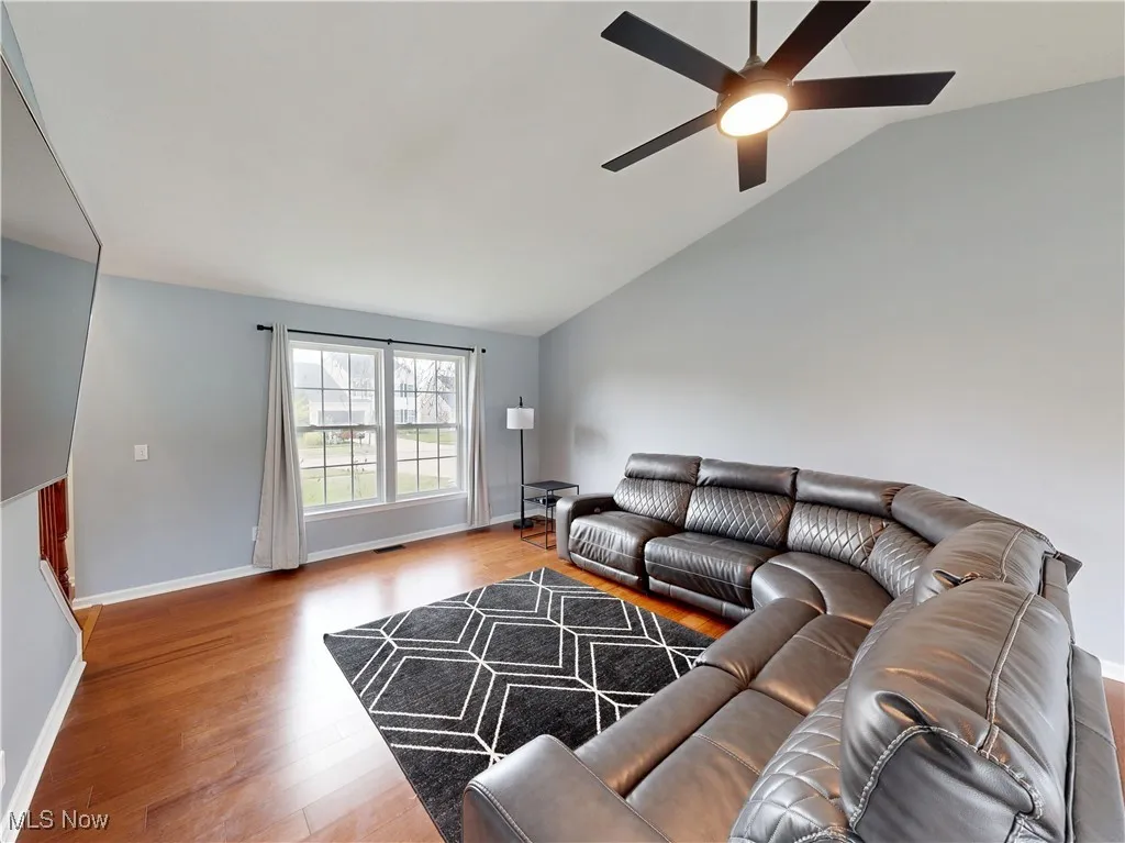 Living room featuring lofted ceiling, wood finished floors, and a ceiling fan