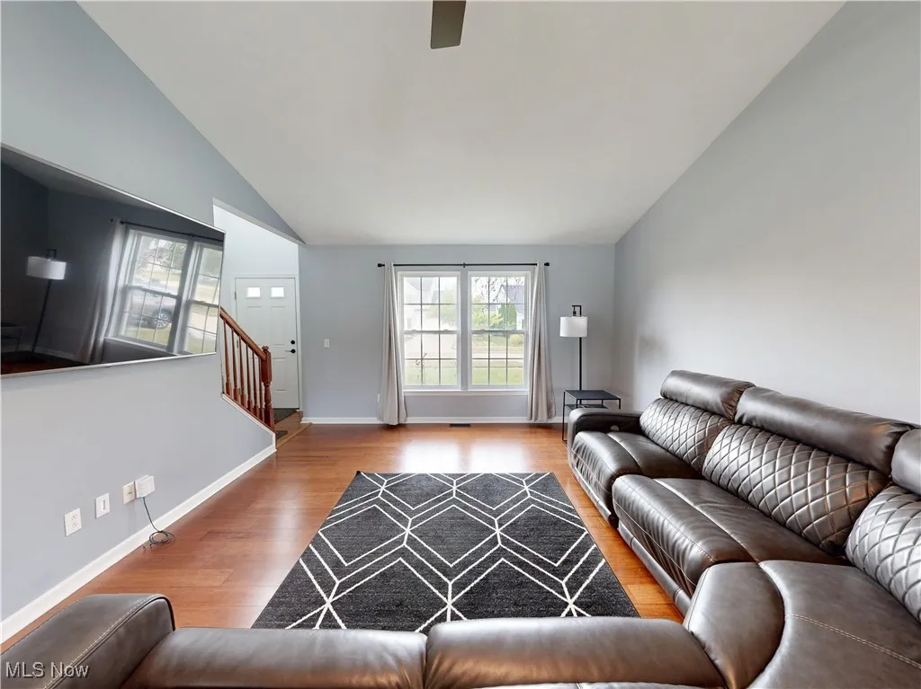 Living area with wood finished floors, stairway, vaulted ceiling, and ceiling fan