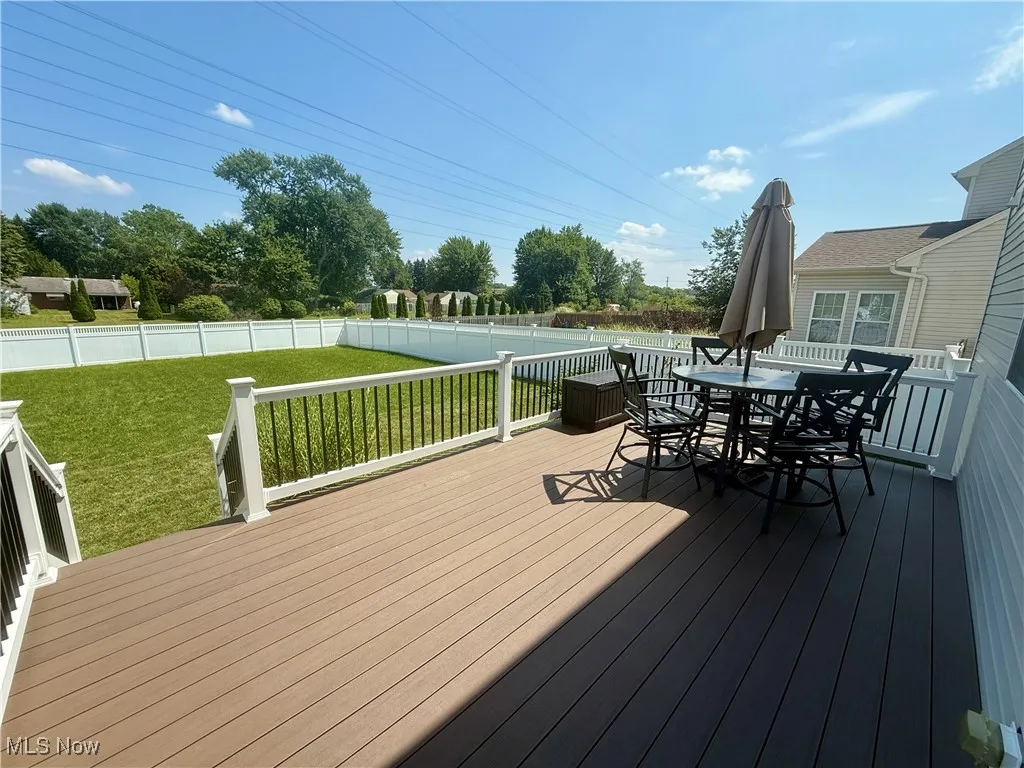 Wooden deck with outdoor dining area and a fenced backyard