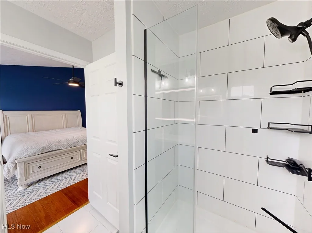 Ensuite bathroom with tiled shower, a textured ceiling, and tile patterned floors