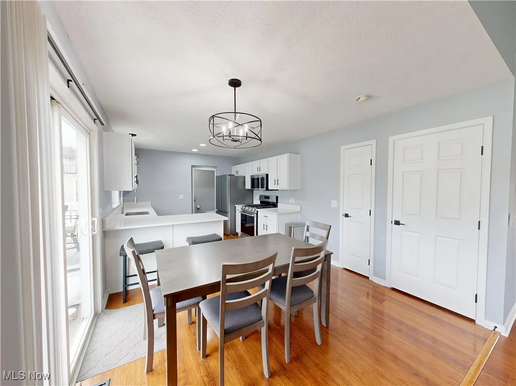 Dining room with light wood-type flooring, a chandelier, recessed lighting, and a textured ceiling