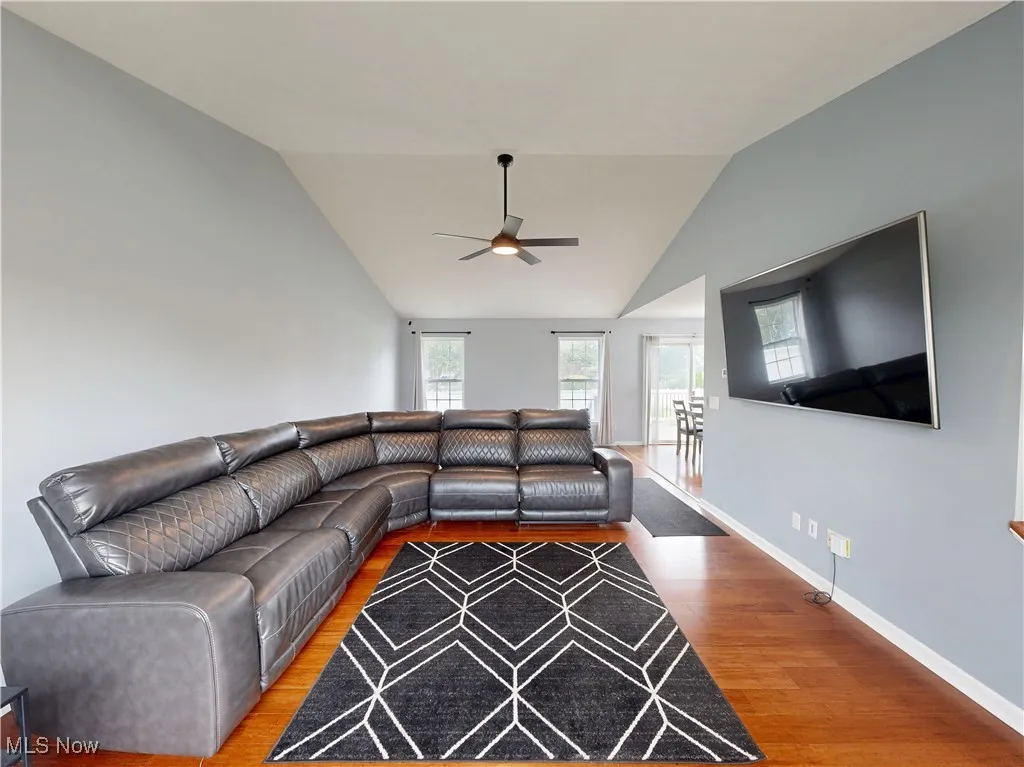 Living room featuring wood finished floors, vaulted ceiling, and ceiling fan