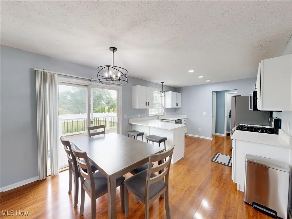 Dining room with light wood-style flooring, a textured ceiling, a chandelier, and recessed lighting