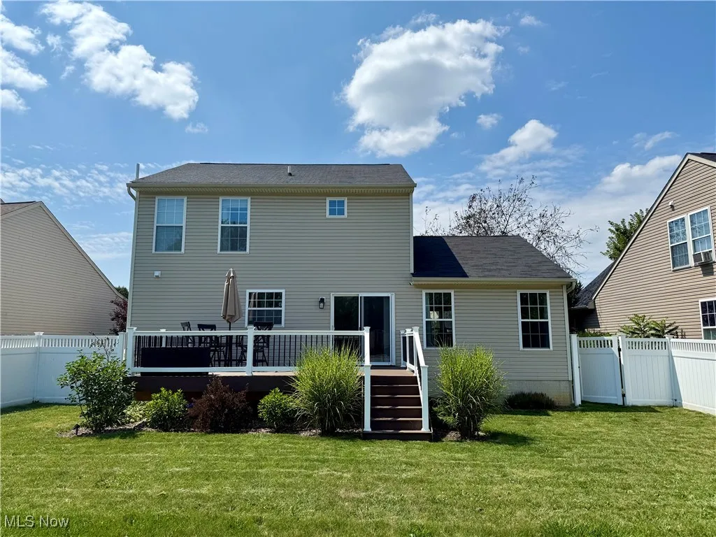Back of property with a fenced backyard, a gate, and a wooden deck