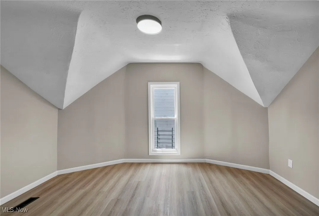 Bonus room with a textured ceiling, wood finished floors, and lofted ceiling
