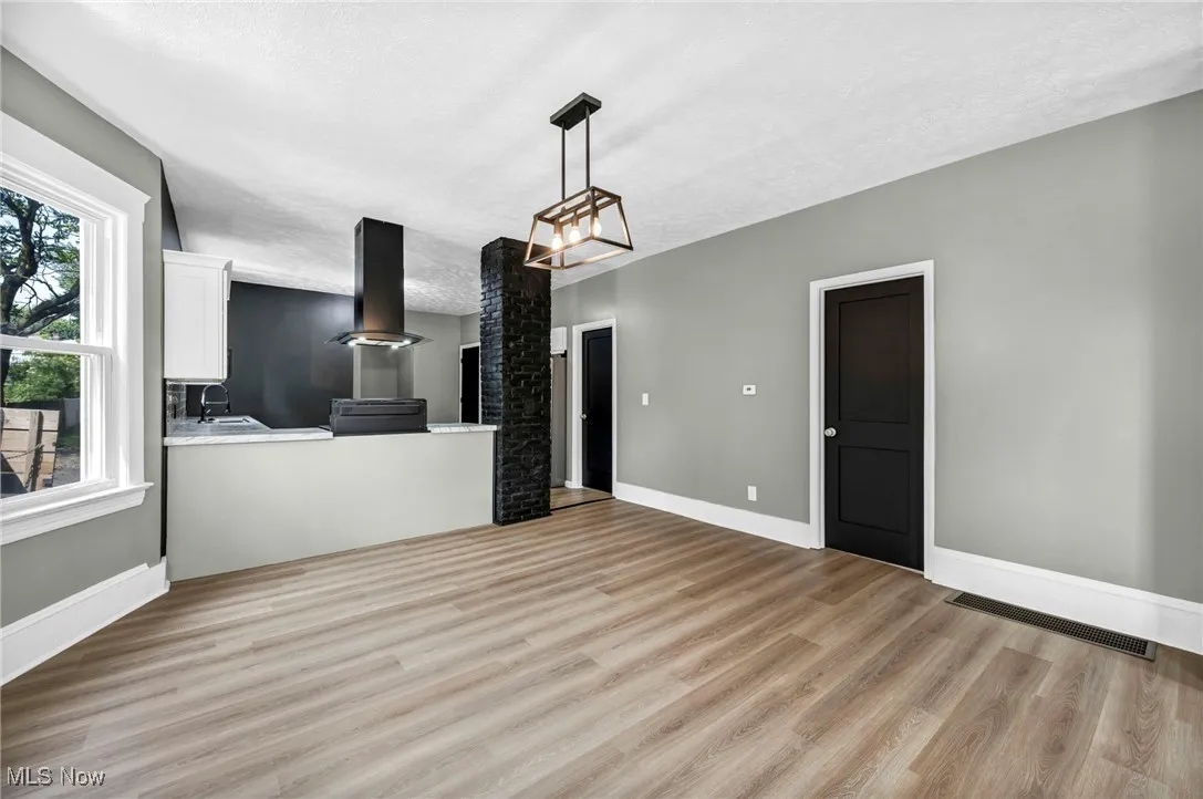 Unfurnished living room with light wood-type flooring, a textured ceiling, and a chandelier