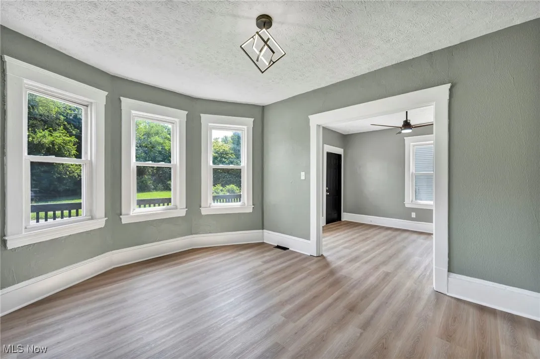 Unfurnished room featuring wood finished floors, a textured ceiling, and a ceiling fan