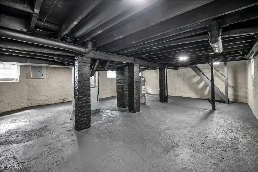 Below grade area with stairs, electric panel, and water heater