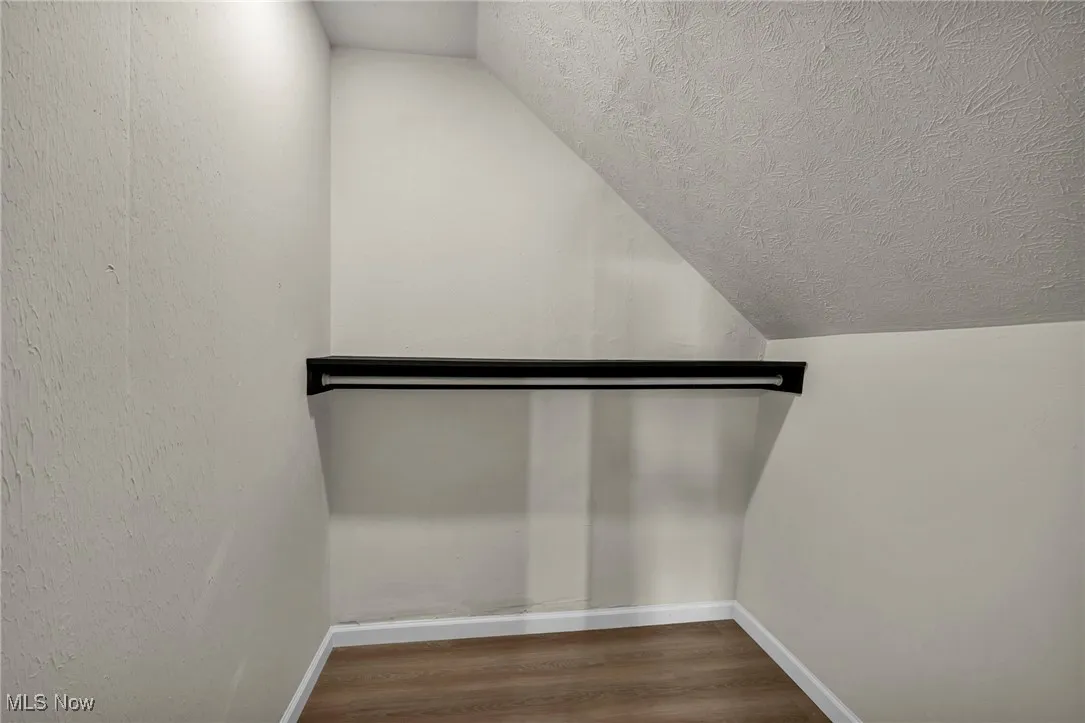 Walk in closet with vaulted ceiling and wood finished floors