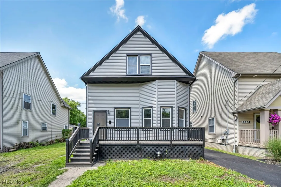 Rear view of house with a wooden deck and a lawn