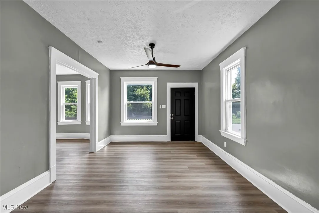 Foyer entrance with ceiling fan, wood finished floors, and a textured ceiling