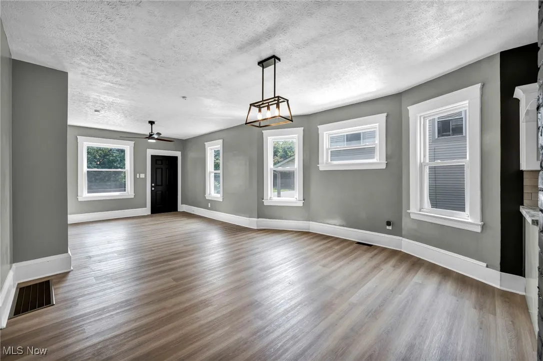 Unfurnished living room with wood finished floors, ceiling fan, a textured ceiling, and a fireplace