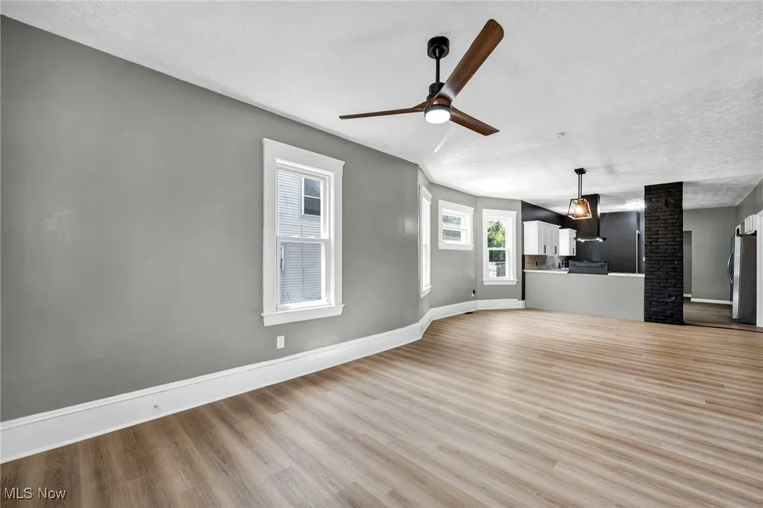 Unfurnished living room with a textured ceiling, wood finished floors, and a ceiling fan