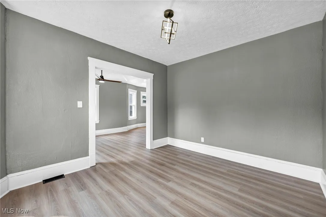 Spare room with wood finished floors, a textured ceiling, and a ceiling fan