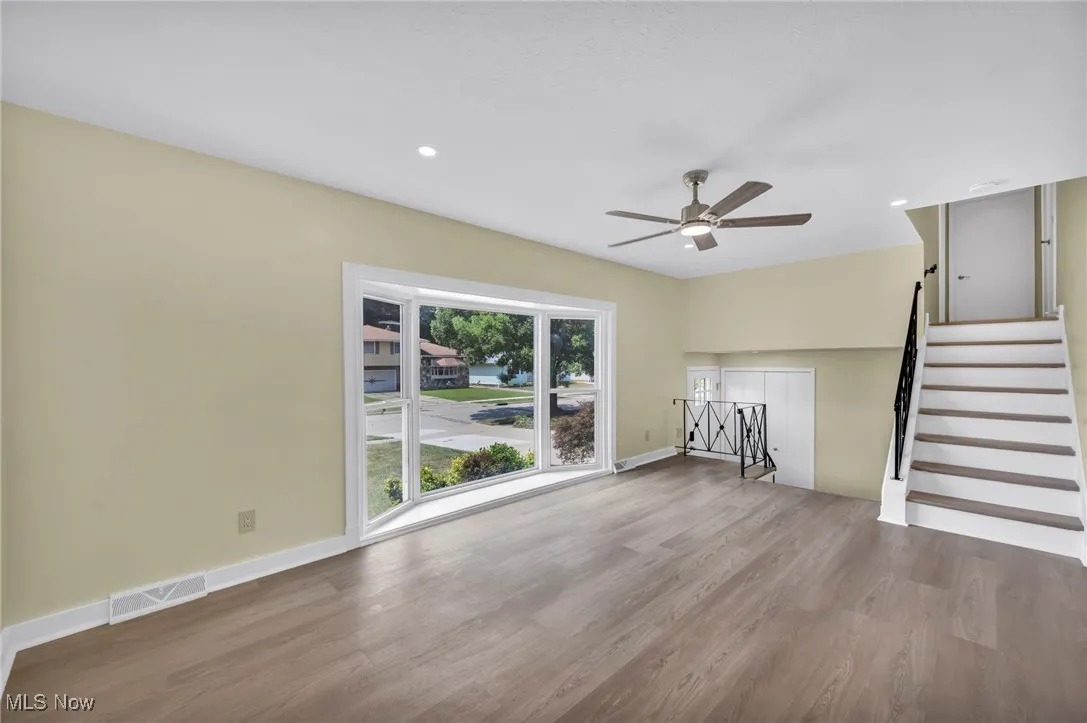 Unfurnished living room featuring stairway, wood finished floors, recessed lighting, and ceiling fan