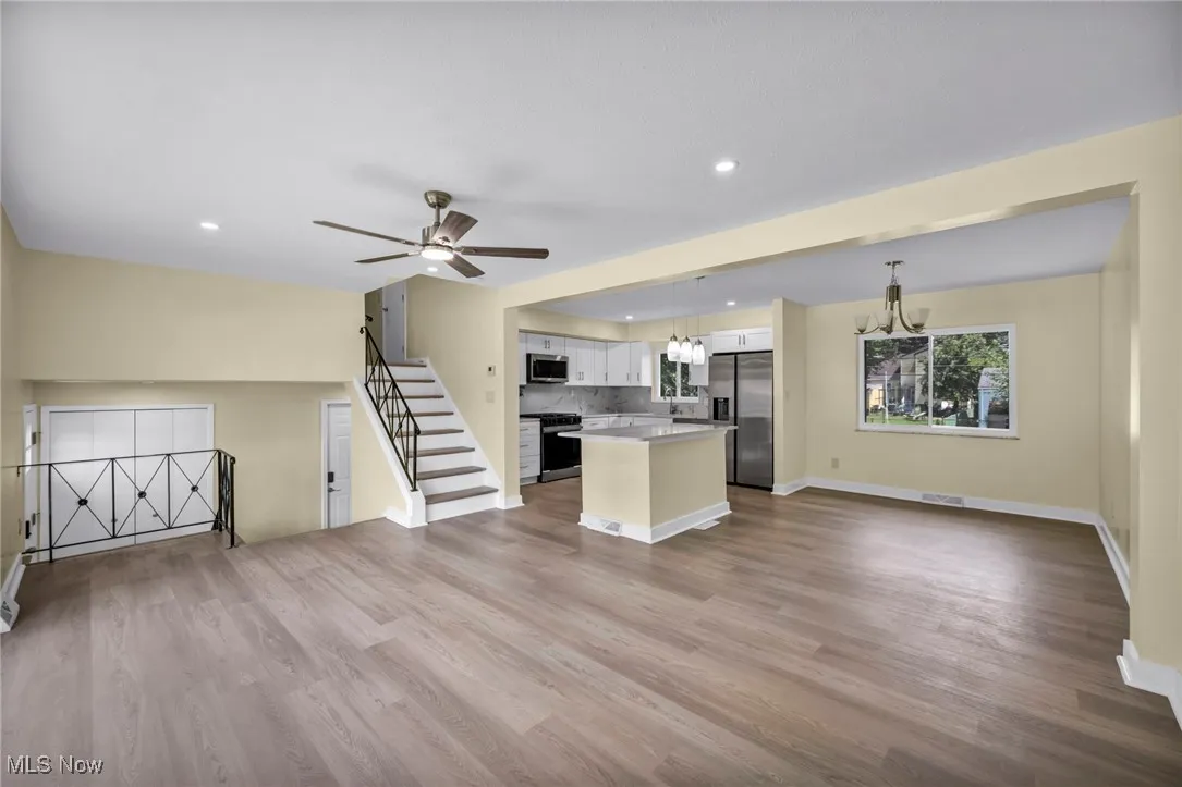 Kitchen featuring open floor plan, a chandelier, white cabinets, appliances with stainless steel finishes, and recessed lighting