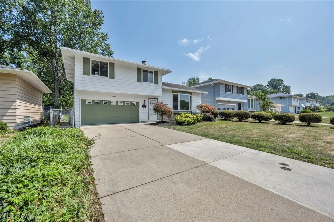 Tri-level home featuring an attached garage, driveway, and a front lawn