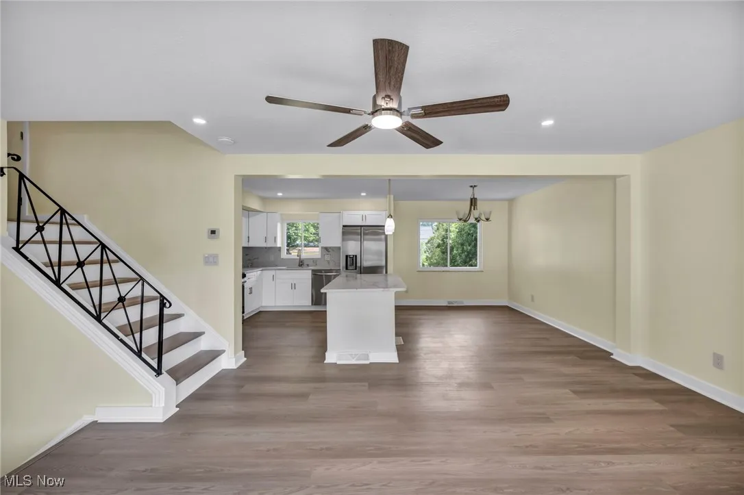 Kitchen with white cabinetry, stainless steel appliances, dark wood-type flooring, backsplash, and recessed lighting