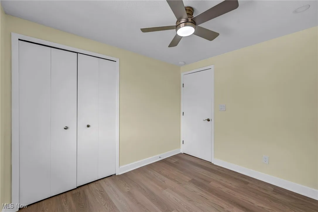 Unfurnished bedroom featuring wood finished floors, a closet, and ceiling fan