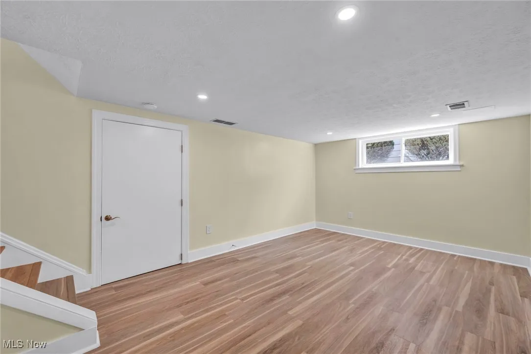 Basement with light wood-type flooring, a textured ceiling, and recessed lighting