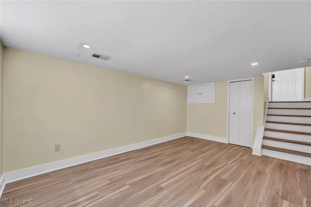 Finished below grade area with light wood-style floors, recessed lighting, and stairs