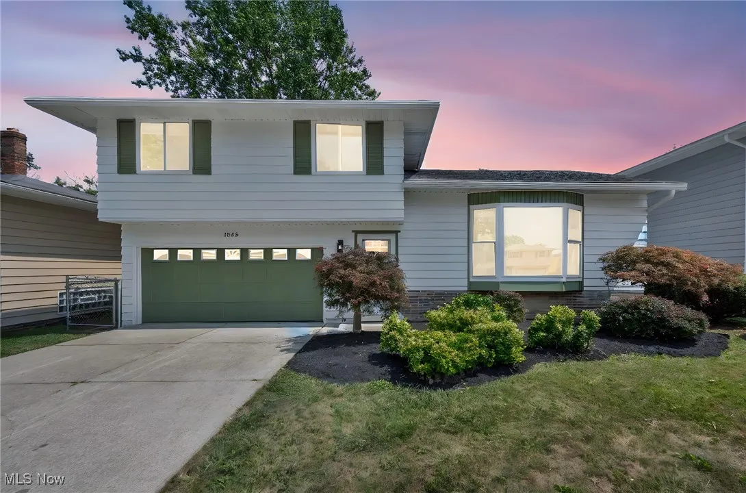 Tri-level home with a garage, concrete driveway, and a front yard