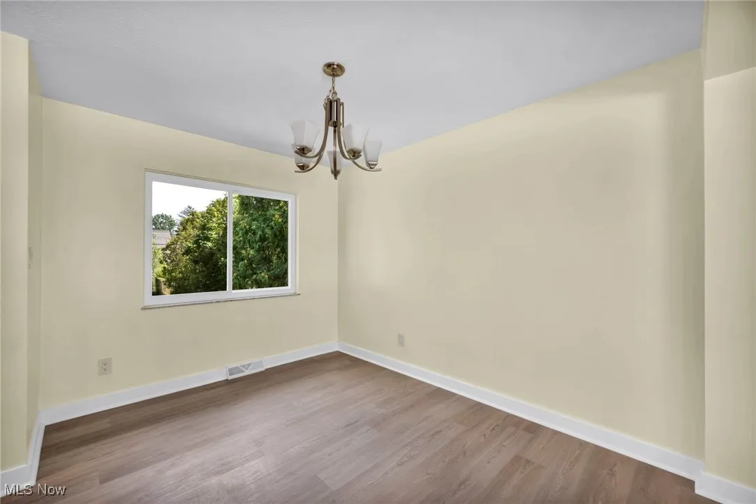 Unfurnished dining area featuring dark wood finished floors and a chandelier