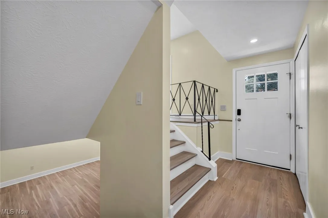 Foyer with wood finished floors, stairway, and recessed lighting