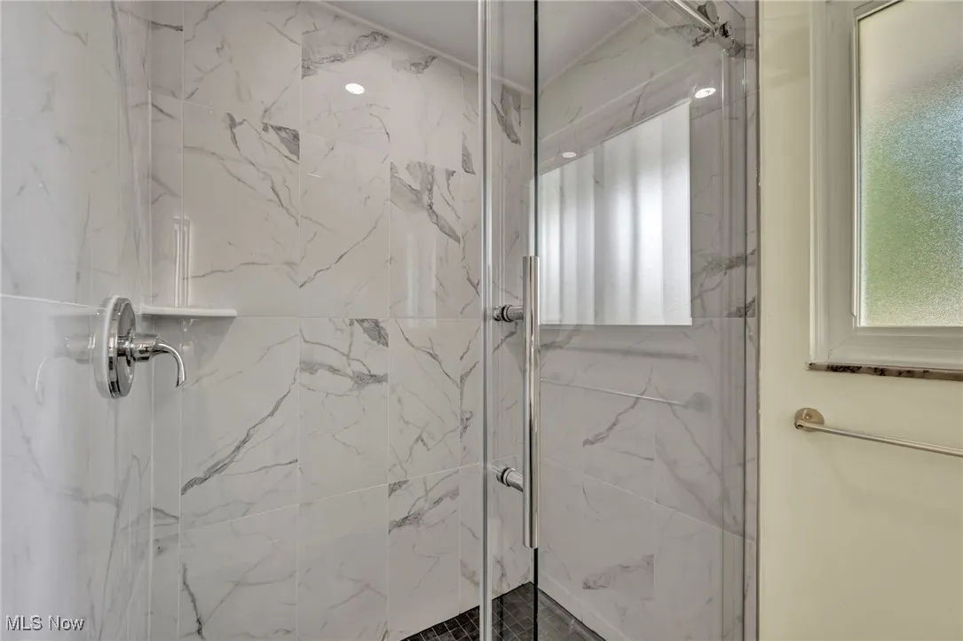 Full bathroom with a marble finish shower and plenty of natural light