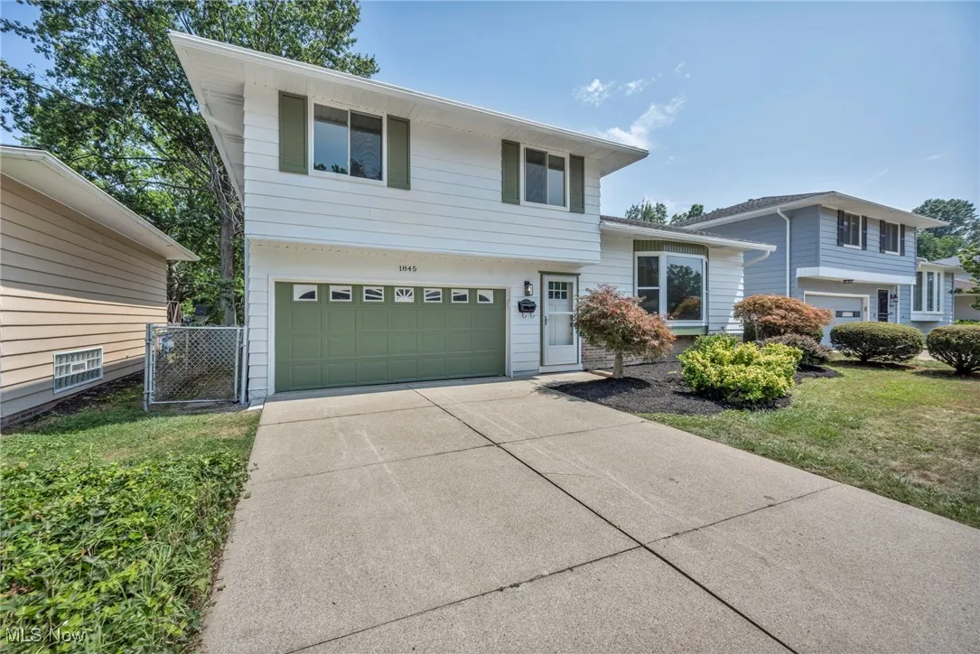 Tri-level home featuring an attached garage, concrete driveway, and a front lawn