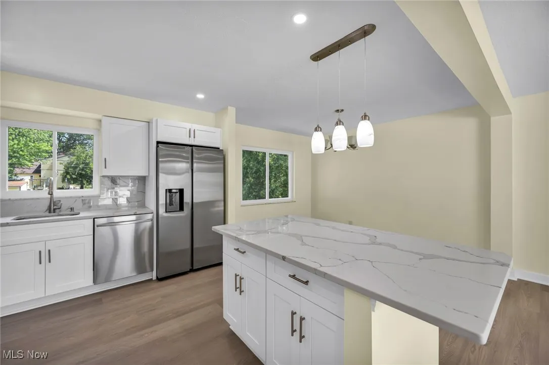Kitchen featuring stainless steel appliances, light wood-type flooring, backsplash, white cabinetry, and recessed lighting