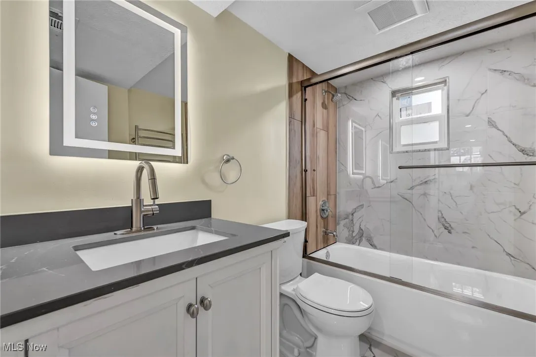 Bathroom with vanity and shower / bath combination with glass door