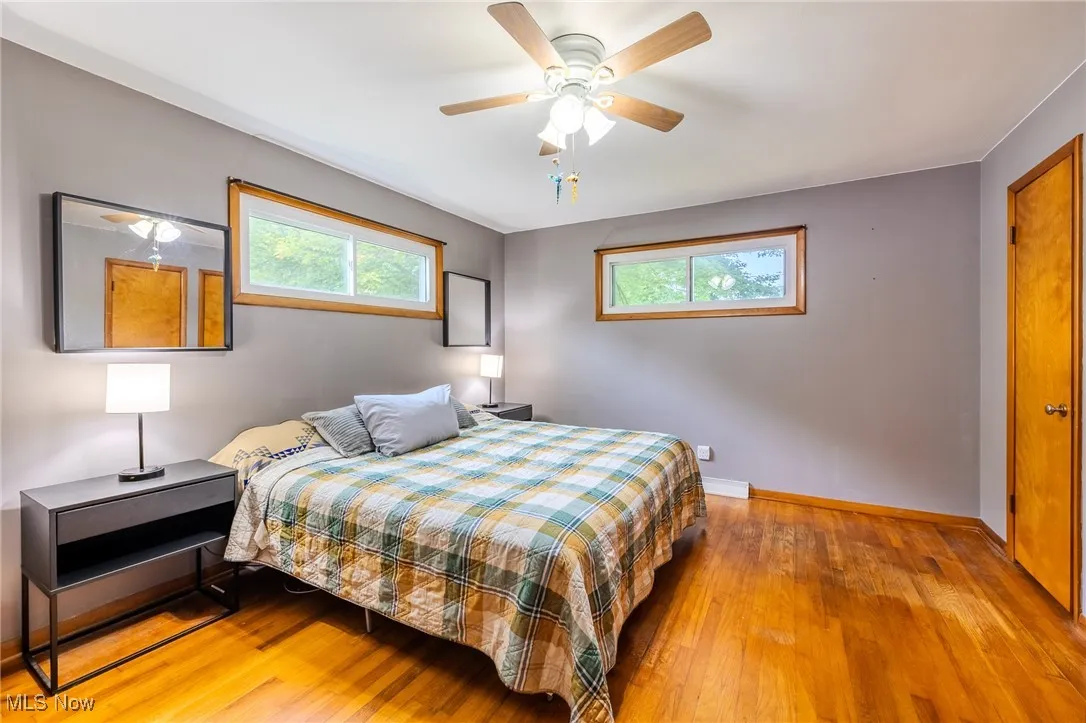 Bedroom with light wood-style floors, multiple windows, and a ceiling fan