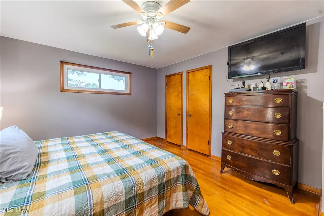Bedroom with light wood-style floors, multiple closets, and ceiling fan