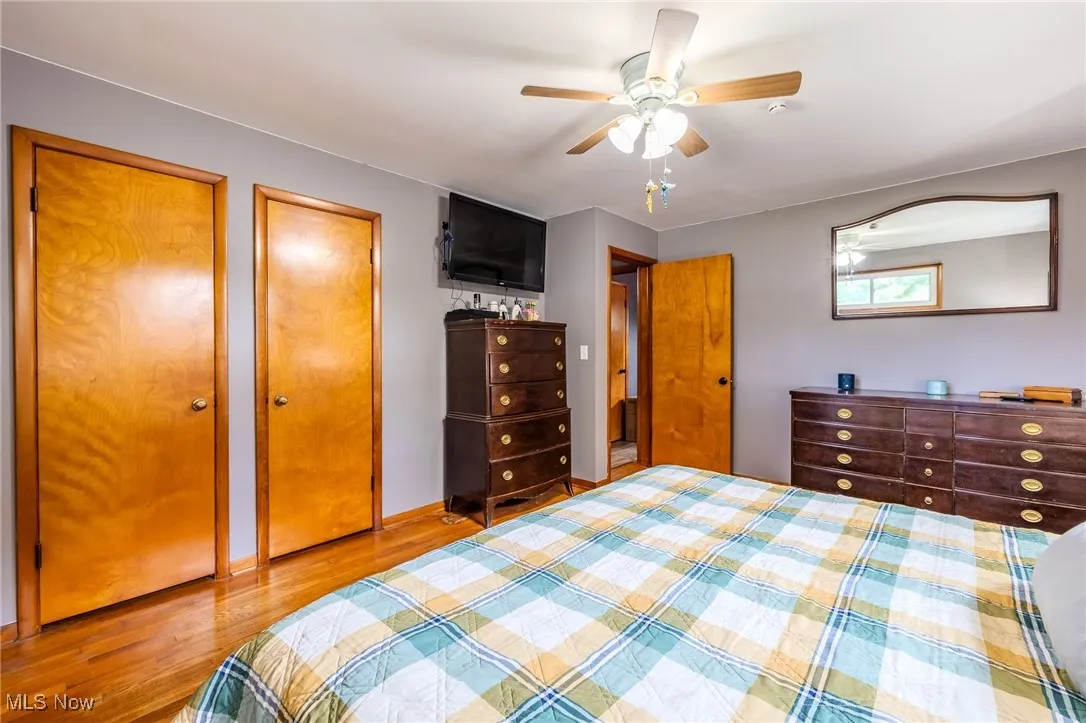 Bedroom with wood finished floors, multiple closets, and a ceiling fan