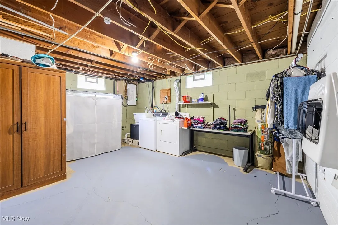 Basement with washer and clothes dryer, heating unit, and electric panel