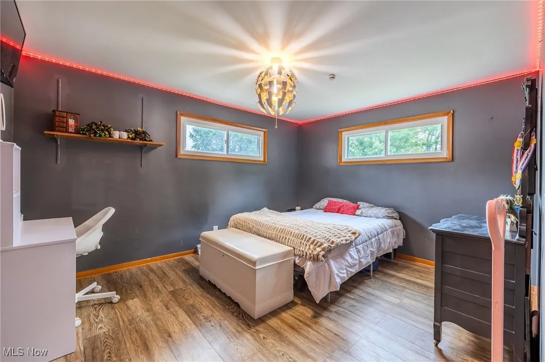 Bedroom featuring hardwood / wood-style flooring, multiple windows, and crown molding