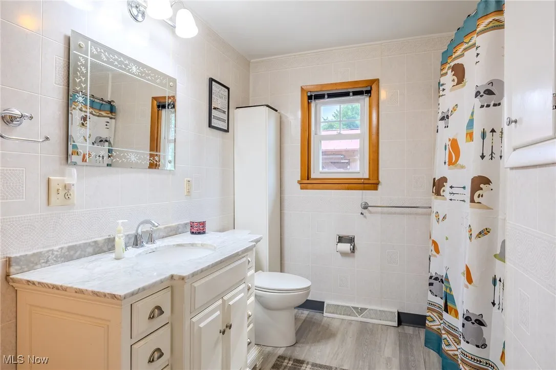 Bathroom featuring tile walls, vanity, and a shower with shower curtain