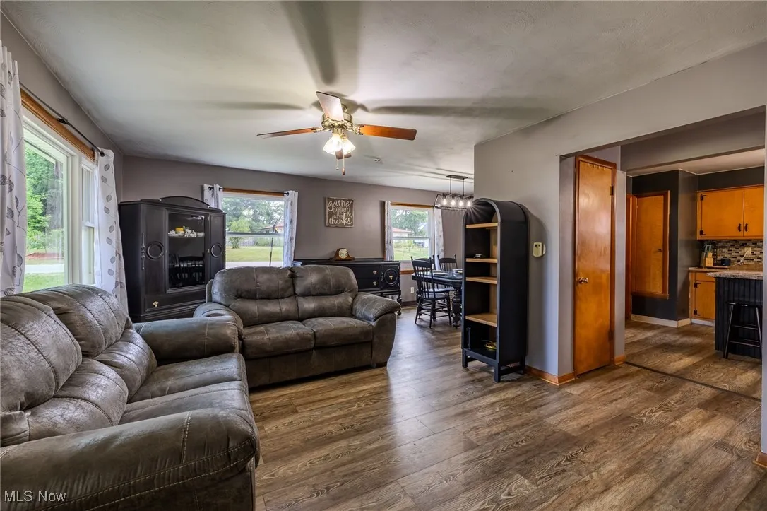 Living area with plenty of natural light, dark wood finished floors, and ceiling fan