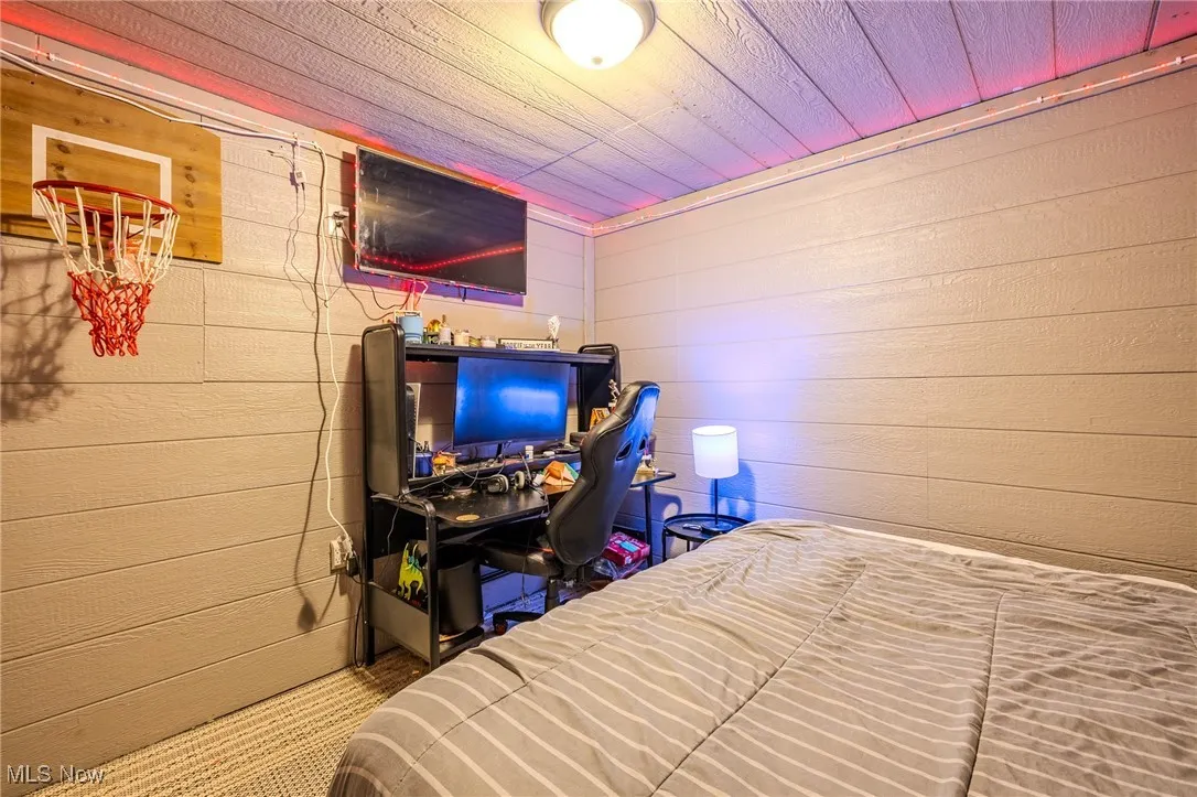 Bedroom with a desk, wooden ceiling, and wooden walls