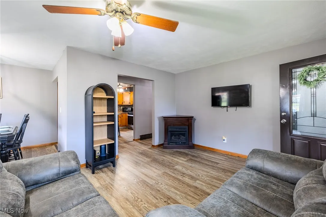 Living area with light wood-type flooring, ceiling fan, and a fireplace