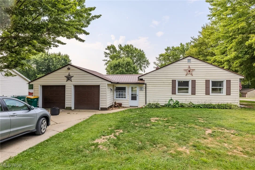 Single story home with a metal roof, a front yard, concrete driveway, and a garage