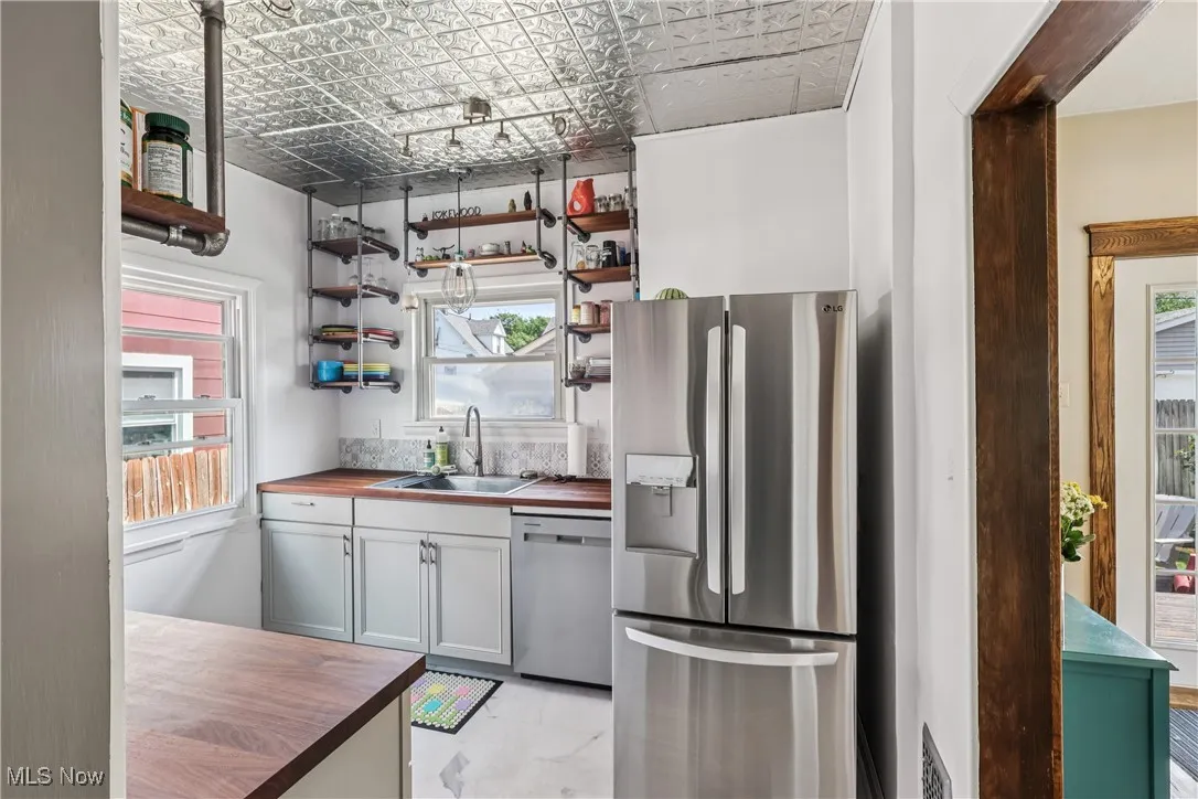 Kitchen featuring wooden counters, stainless steel appliances, open shelves, and an ornate ceiling