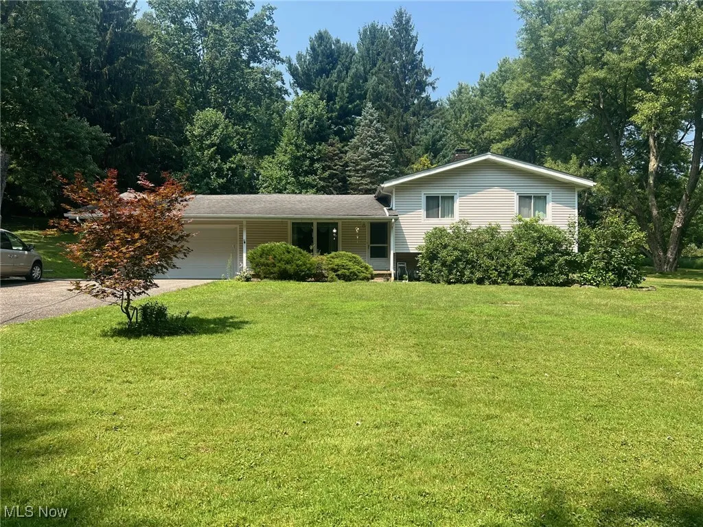 Split-level home with a garage, a front lawn, and driveway