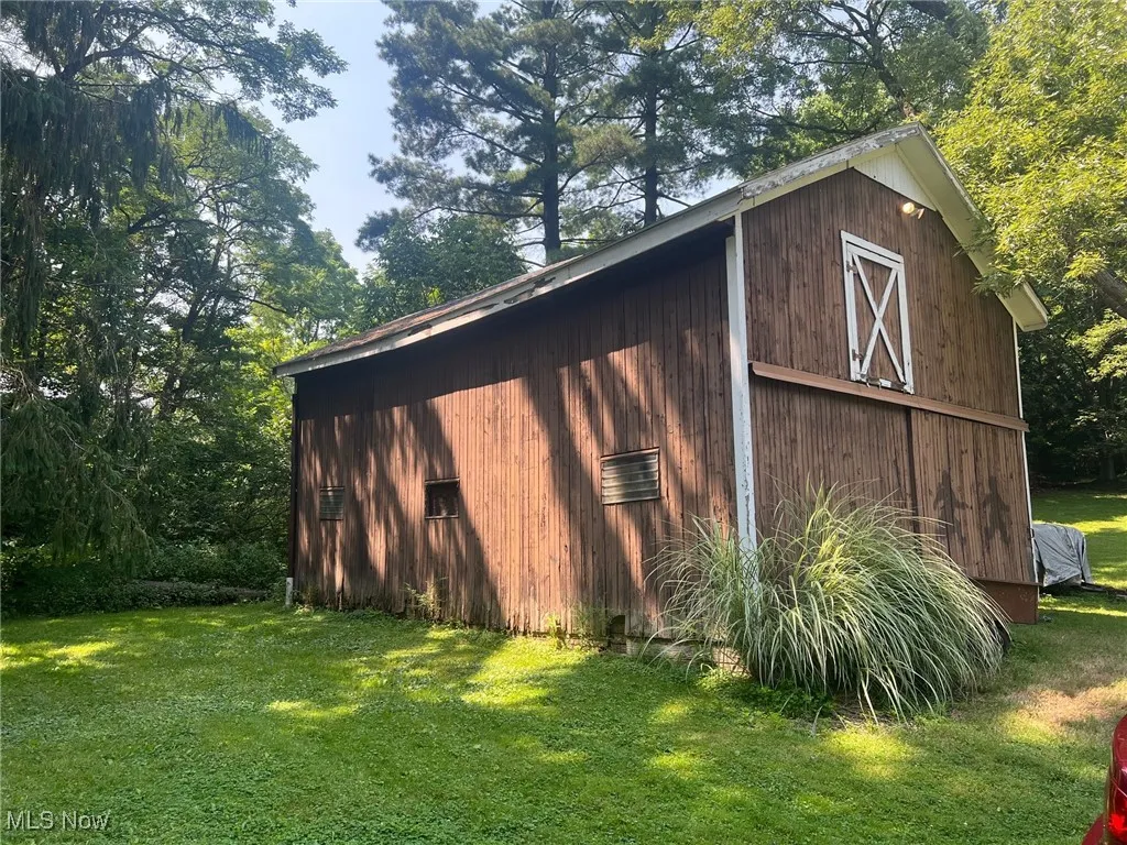 View of barn with a yard and view of scattered trees