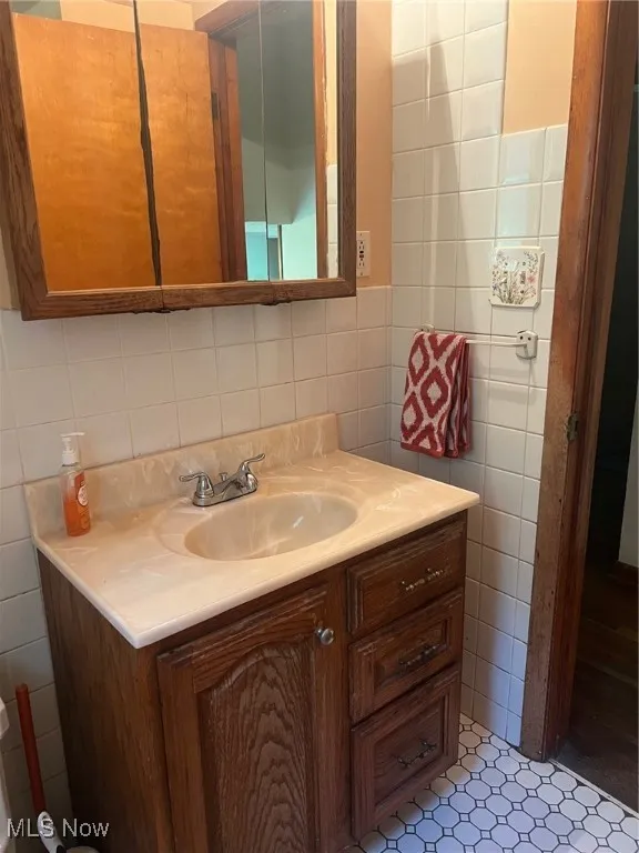 Bathroom featuring tile walls, vanity, and tile flooring