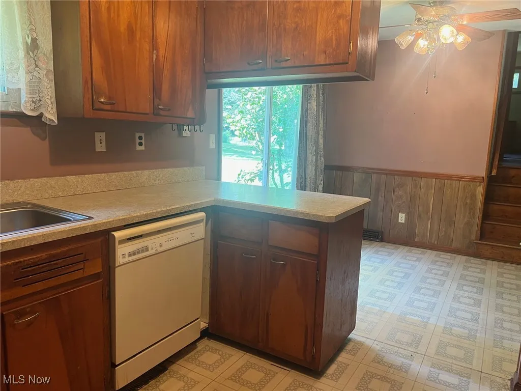 Kitchen featuring wooden walls, light countertops, and a peninsula