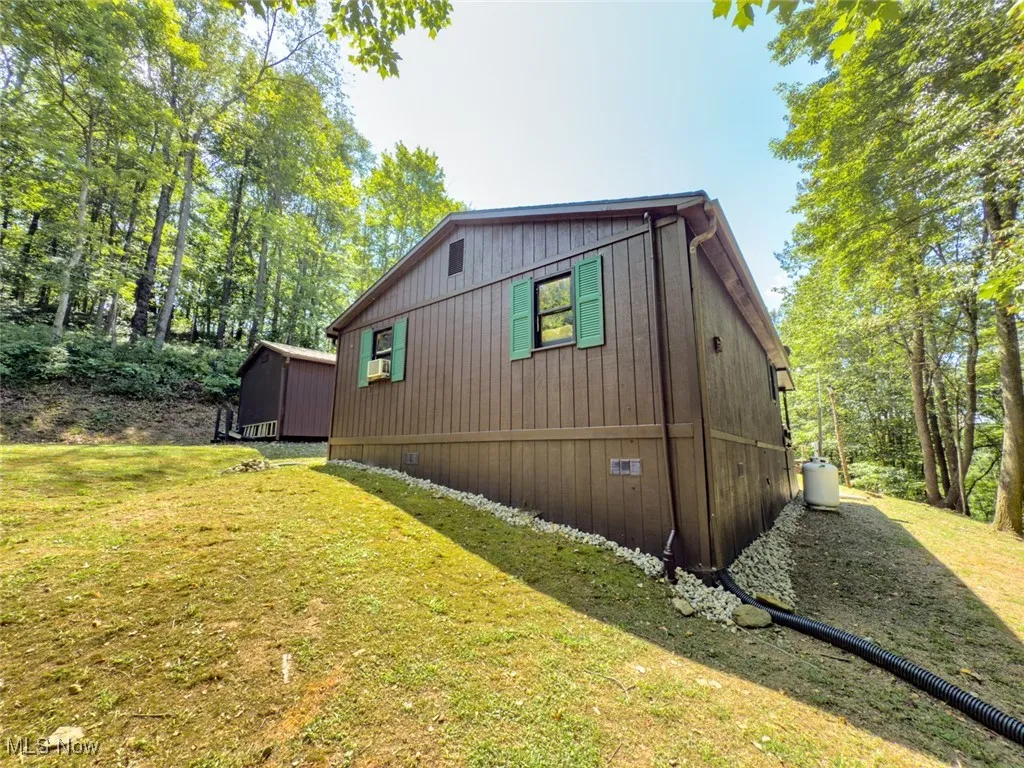 View of side of property featuring a yard and view of scattered trees