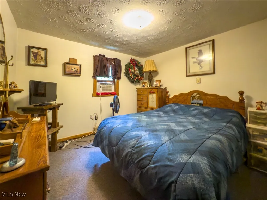 Bedroom featuring a textured ceiling, carpet, and cooling unit