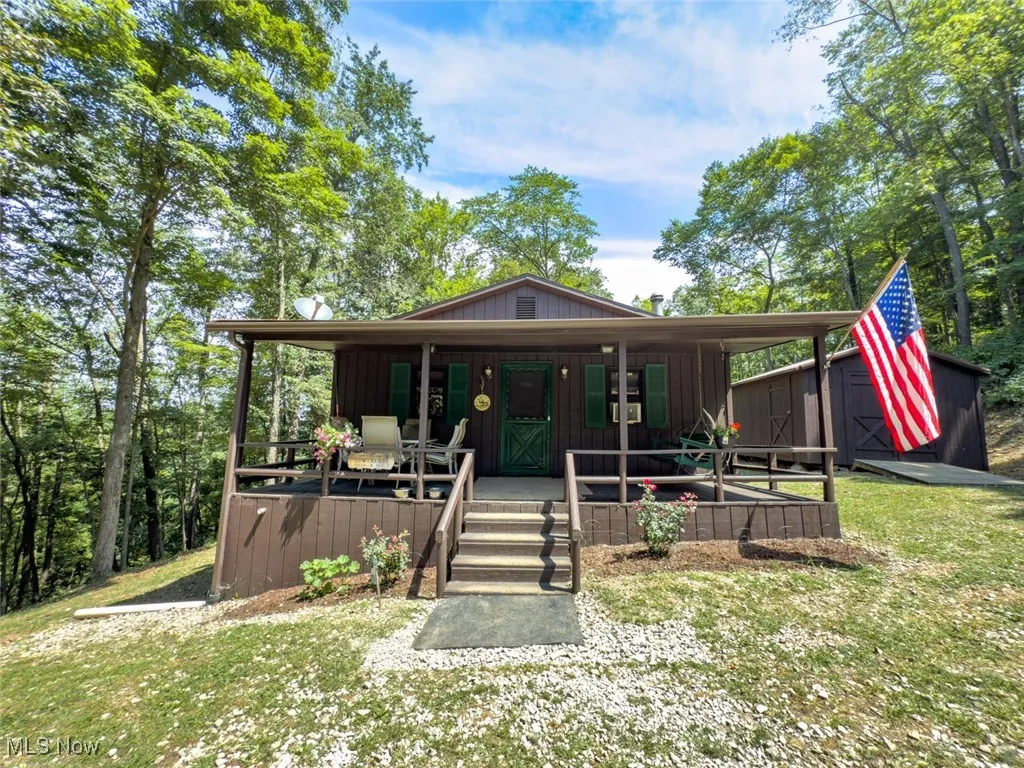 Rustic home with a porch, board and batten siding, and an outbuilding
